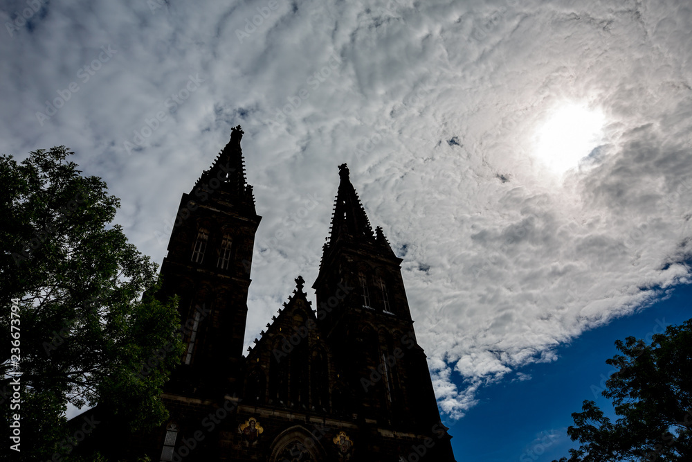 Weird and impressive summer sky with layered puffy clouds and cathedral silhouettes of two towers with crosses in Prague, capital of Czech Republic