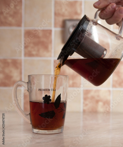 Glass teapot and glass cup with tea on the table photo