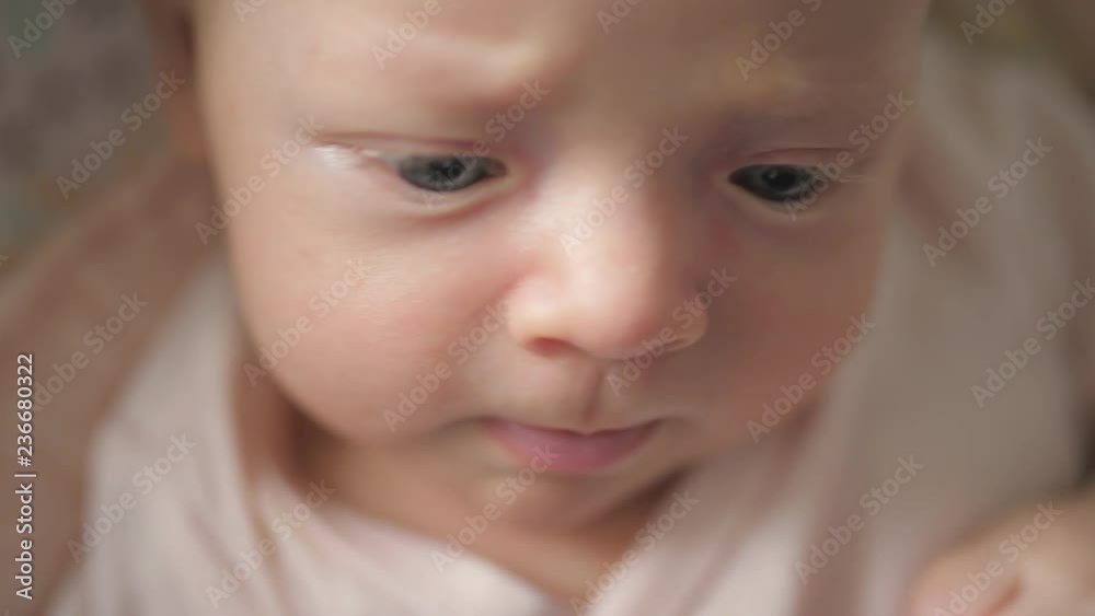 Close up shot of a newborn baby girl making faces while she sits in her baby chair Close up shot of a newborn baby girl making faces while she sits in her baby chair