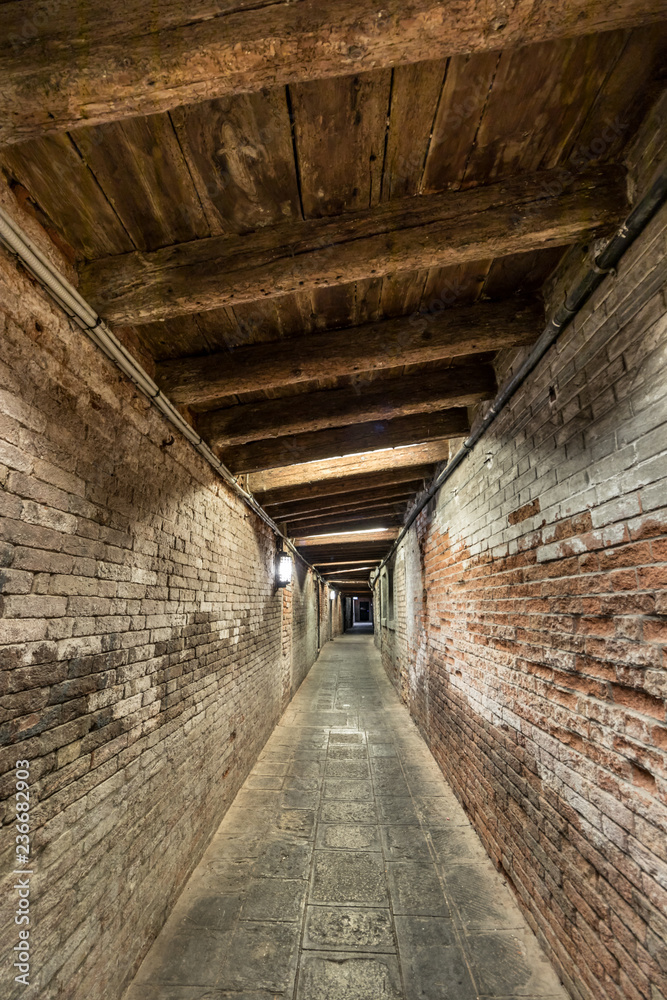 A narrow street - passage with a wooden roof in the ceity center of Venice, Italy.