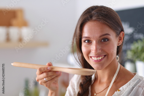 Cooking woman in kitchen with wooden spoon. Cooking woman