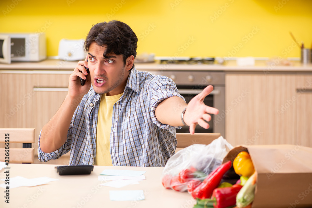 Young man calculating expences for vegetables in kitchen Young man calculating expences for vegetables in kitchen