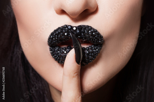 Women's lips with black lipstick and rhinestones make tin Shhh. Black lipstick and black and white manicure photo