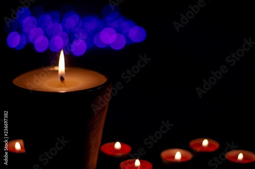 Candle with flame and bokeh light in dark background for praying in Church concept.