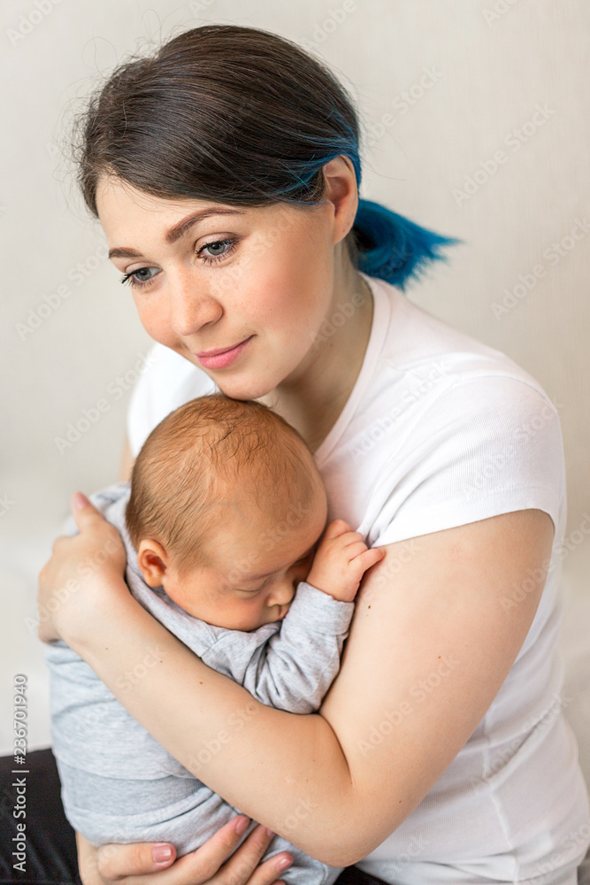 Young mother holding her newborn child. Mom nursing baby.