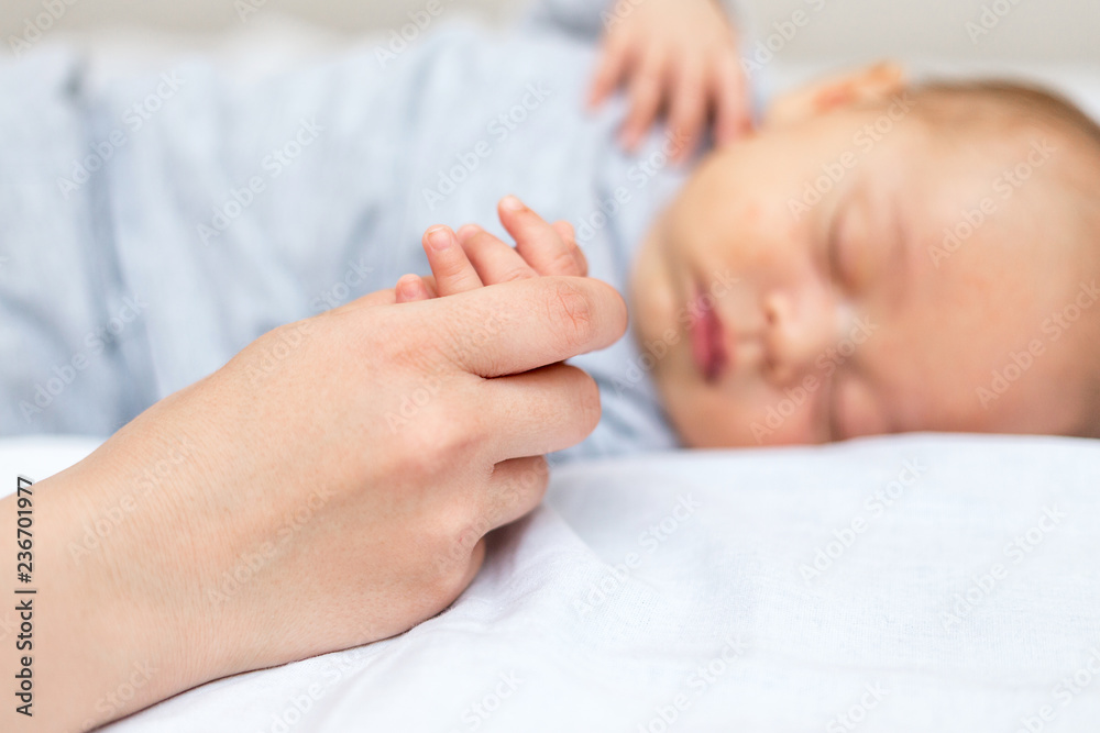 Young mother holding her newborn child hand Young mother holding her newborn child hand