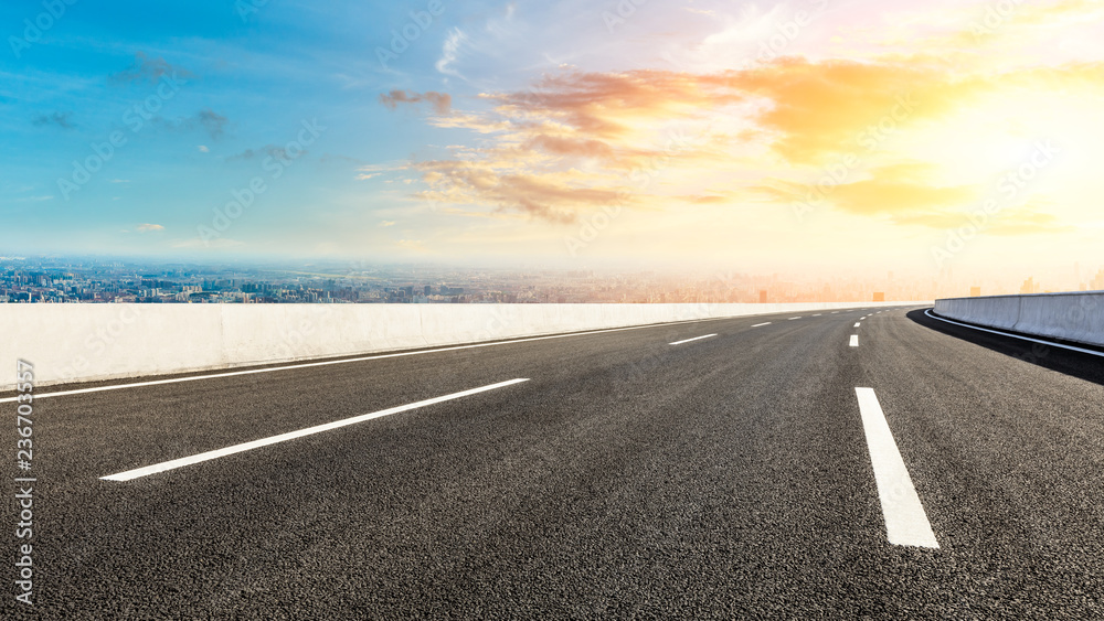 Panoramic city skyline and buildings with empty asphalt road at sunset