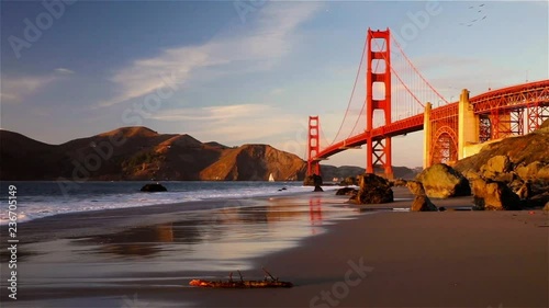 Panning view of the Golden Gate Bridge and the Pacific Ocean from the hidden and secluded rocky Marshall's Beach at sunset in San Francisco, California