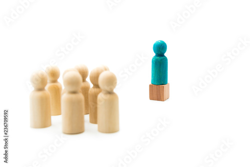 Wooden figures as a group listening to one blue figure helding speech, isolated on white background photo