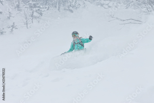 Woman snowboarder freerider goes down on powder snow in the mountains in a snowfall