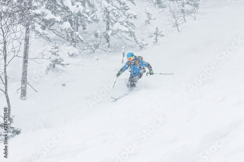 man skier freerider goes down on powder snow in the mountains in a snowfall
