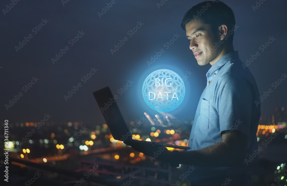 Fototapeta premium Businessman stand on roof top using laptop with Big data hologram on his hand and element of this image furnished,smart city and network connect concept