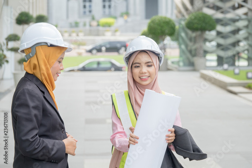 Professional woman engineers are discussing on construction at outdoor.