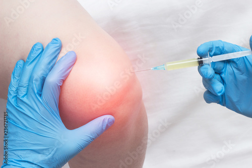 The doctor injects plasma into a sore, inflamed female knee for arthrosis and arthritis, plasma-lifting, close-up, medical, professional