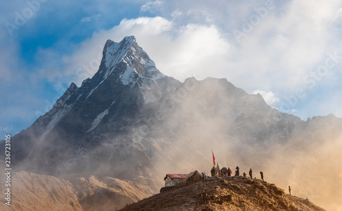 Hiker reaches the mountain peak of Machapuchare. A mountain in the Annapurna Himalayas of north central Nepal photo