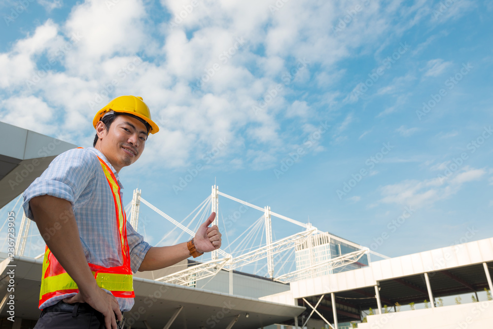 custom made wallpaper toronto digitalYoung confidence engineer wearing yellow safety helmet showing thumb up look at camera in front construction building.