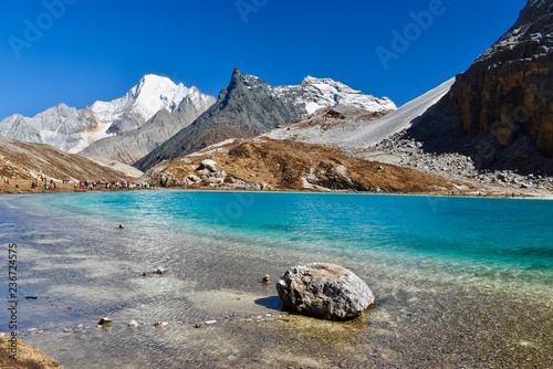 Unique colored Milk lake (approx. 4300m altitude) with blue sky and sharp mountains around it - sacred Mt. Chanadorje (Xianuoduoji,5958m) on the left. Daocheng Yading Nature Reserve, Sichuan, China.   photo