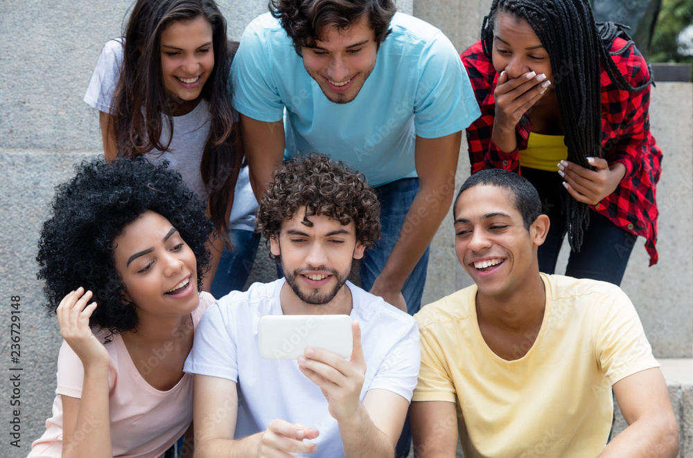 Obraz premium Group of international young adults gaming with phone