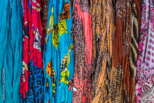 Variety of colorful scarfs hanging together, forming a background.