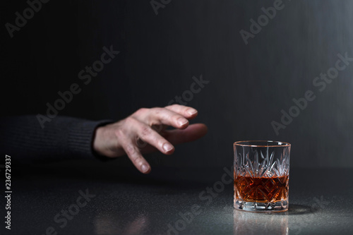 Man's hand reaches for a glass of alcohol. photo