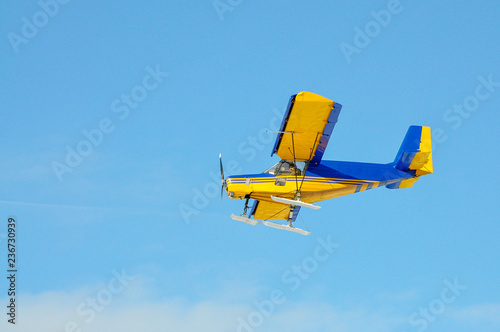 A yellow plane with a propeller on the blue sky