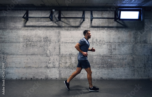 Sporty man in sportswear running indoors. When you feel quitting, think about you started.