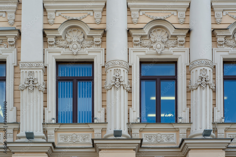The facade of an old building decorated with stucco with windows
