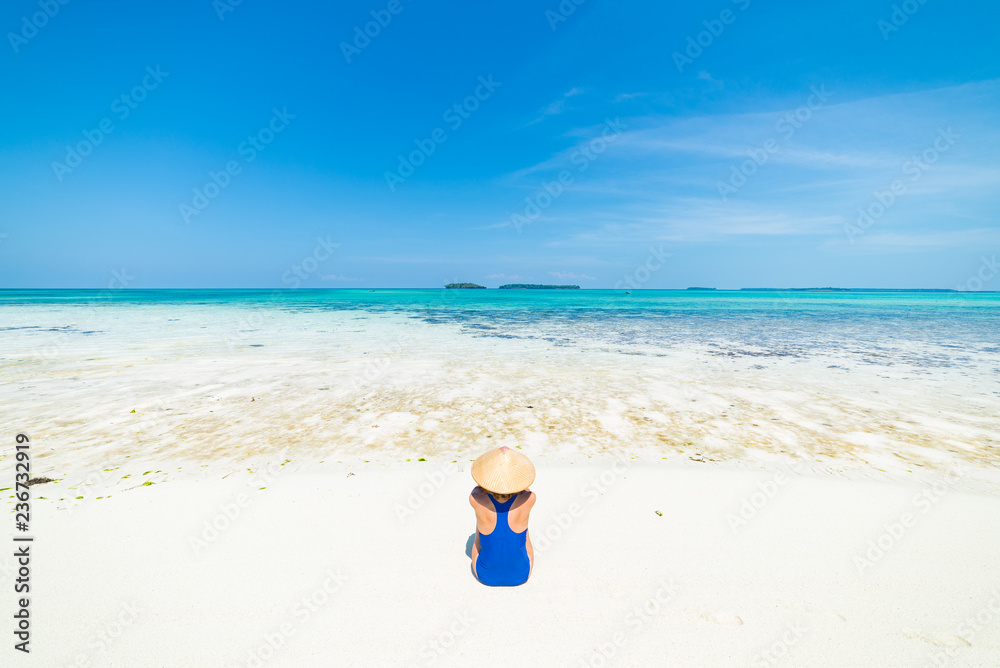 Woman sunbathing on scenic white sand beach, rear view, sunny day, turquoise transparent water, real people. Indonesia, Kei islands, Moluccas Maluku Woman sunbathing on scenic white sand beach, rear view, sunny day, turquoise transparent water, real people. Indonesia, Kei islands, Moluccas Maluku