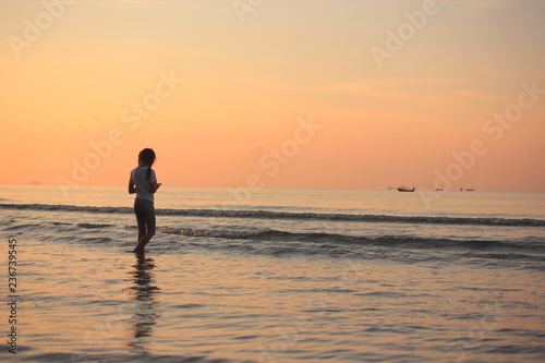 Child girl is relax playing on the beach and Happy child girl on the sunset. 