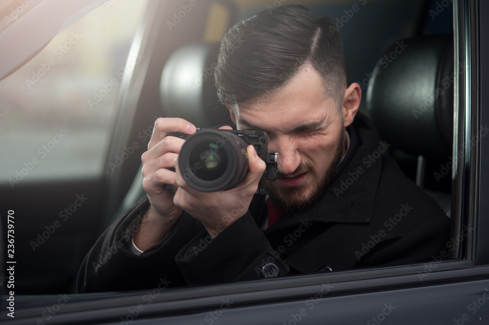 Close-up - Young Man Photorapher Sitting In The Car And Quickly Took A Photo On A Digital Camera. Concept Of Espionage And Photography Close-up - Young Man Photorapher Sitting In The Car And Quickly Took A Photo On A Digital Camera. Concept Of Espionage And Photography