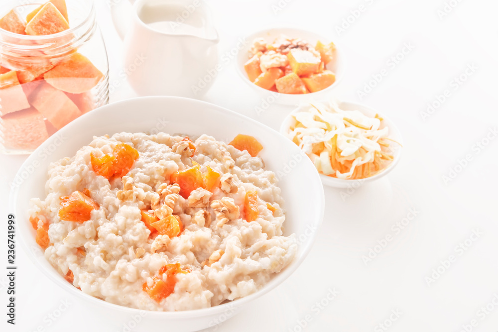 Oatmeal with pumpkin and nuts in a plate, vegetable salad and a jug with milk on a white background. Close-up. Copy space Oatmeal with pumpkin and nuts in a plate, vegetable salad and a jug with milk on a white background. Close-up. Copy space