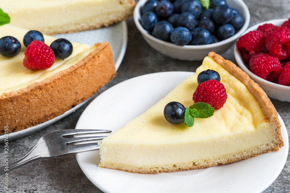 slice of New York cheesecake with fresh berries and mint with fork on stone background. close up slice of New York cheesecake with fresh berries and mint with fork on stone background. close up