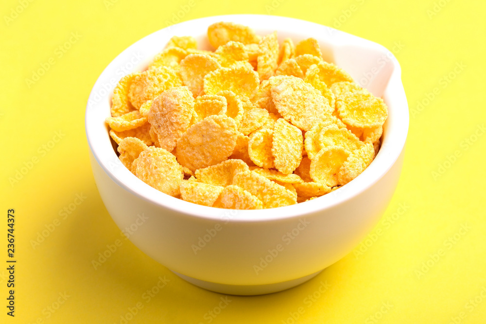 Crispy corn flakes in clay bowl on bright yellow background Crispy corn flakes in clay bowl on bright yellow background