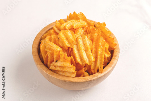 Crunchy corrugated potato chips in wooden bowl