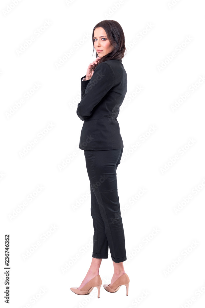Back side view of elegant sexy business woman turning and looking at camera in black suit. Full body isolated on white background. Back side view of elegant sexy business woman turning and looking at camera in black suit. Full body isolated on white background.