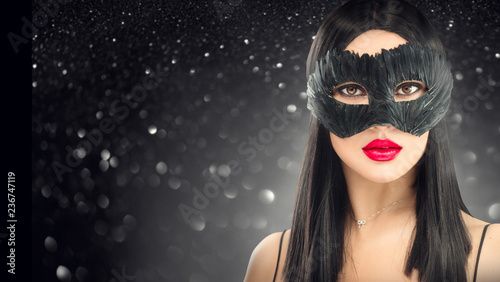 Beauty glamour brunette woman wearing carnival dark mask, party over holiday glowing black background