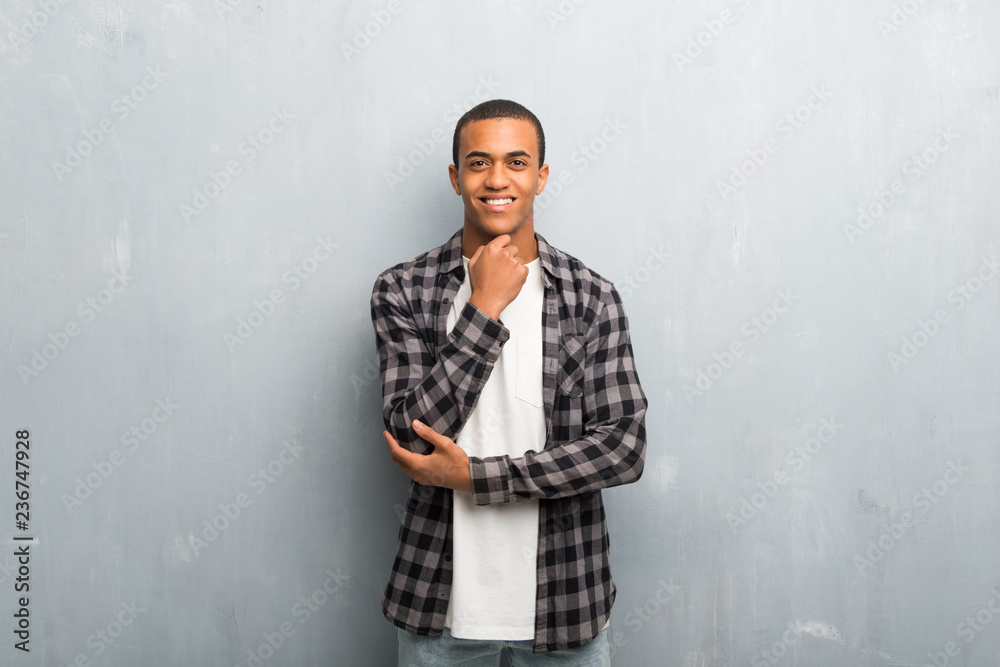 Obraz premium Young african american man with checkered shirt smiling and looking to the front with confident face