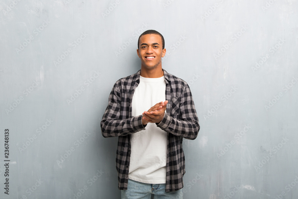 Young african american man with checkered shirt applauding after presentation in a conference