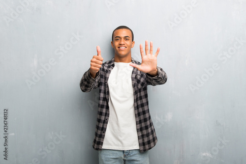 Young african american man with checkered shirt counting six with fingers