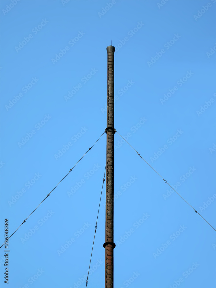 Obraz premium high industrial black metallic pipe on blue sky in sunny day, vintage construction diversity