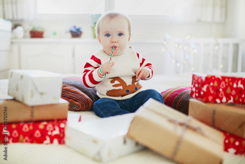 Naklejka premium Happy little baby girl opening Christmas presents on her very first Christmas