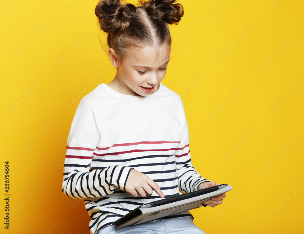 Little girl with tablet on yellow studio background. Little girl with tablet on yellow studio background.