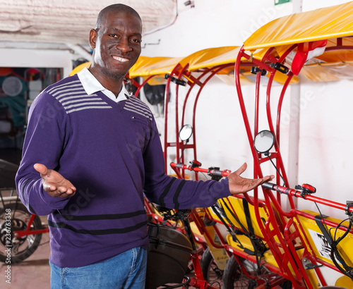 Glad driver of pedicab offering touristic tour photo