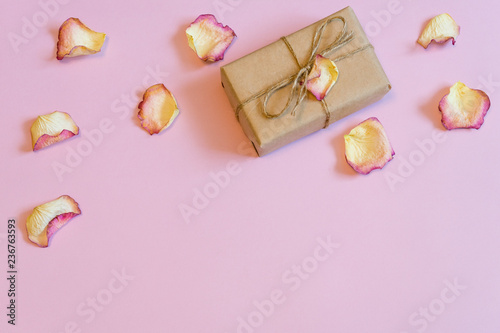 Gift box wrapping in kraft paper with dried cream rose petals on