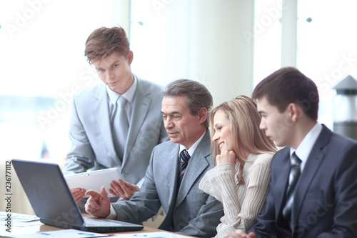 businessman points his hand at the laptop screen to show information to colleagues