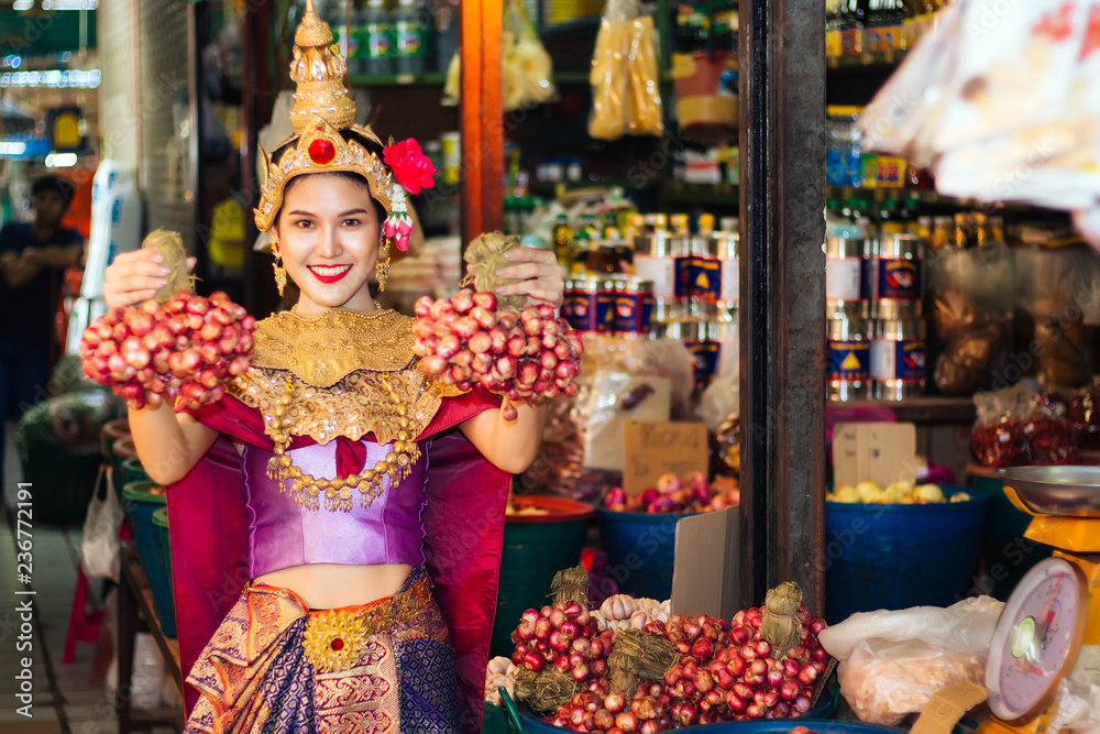 Woman wearing Thai style dress are Holding shallots in market. Woman wearing Thai style dress are Holding shallots in market.