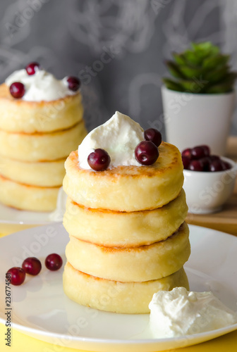 Cottage cheese pancakes with sour cream and berries on yellow background. Syrniki. Russian food. Copy space