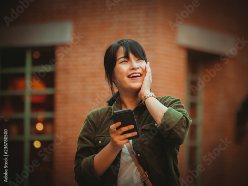 Asian woman using smartphone with happy mood in shopping mall