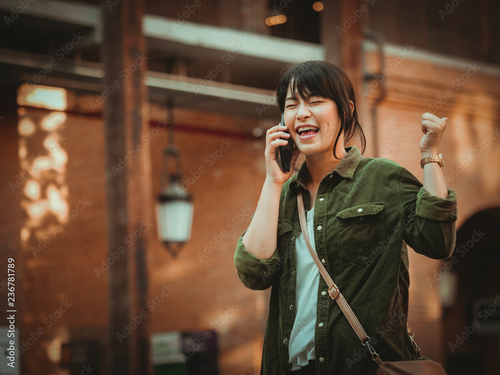 Fototapeta premium Asian woman using smartphone with happy mood in shopping mall