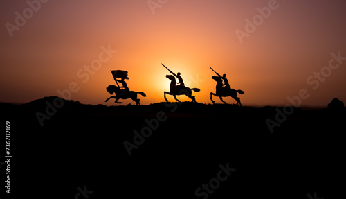 Attacking scene. War concept. Riders on horse ready to fight and soldiers on a dark foggy toned sunset background. Battle scene battlefield of fighting soldiers.